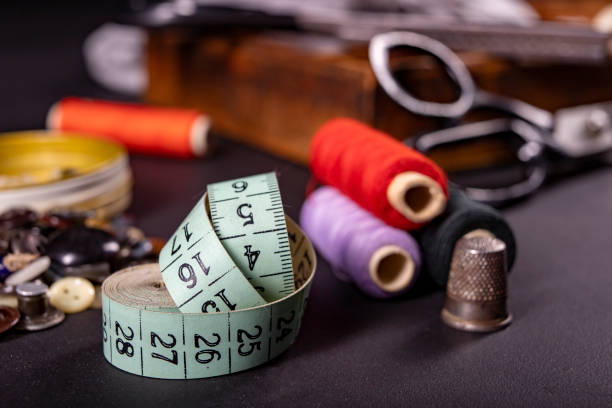 istock Utensils on the table in the tailor's workshop. Accessories necessary for tailoring. Dark background. 1303557189
