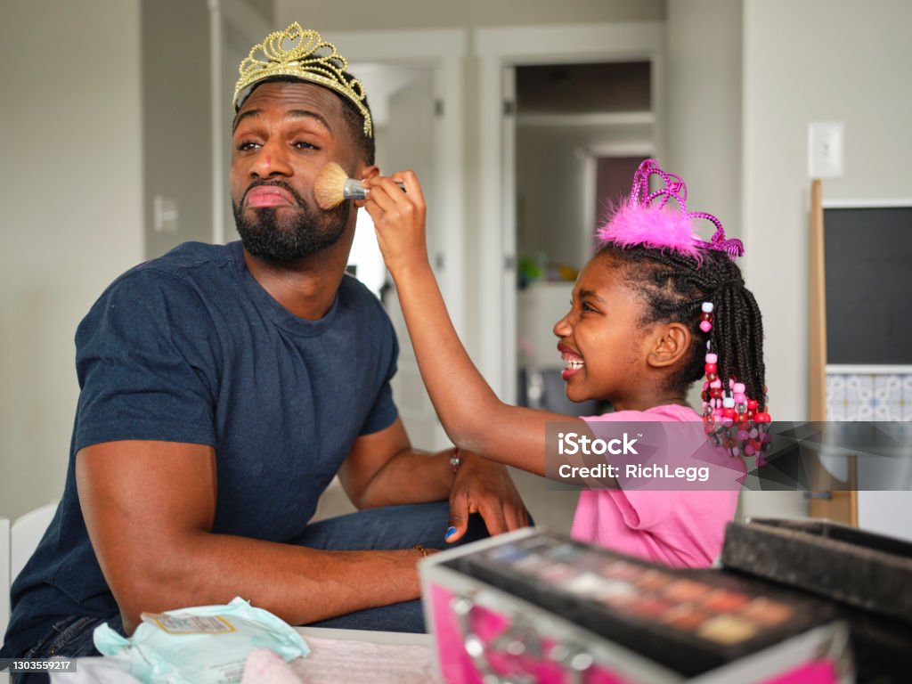 Dad and Daughter Playtime Dress-up and Putting on Makeup An African American father and daughter playing dress up and putting on makeup n their home. Father Stock Photo