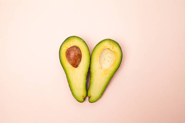 istock Halved and whole avocados on pink table 1303559431