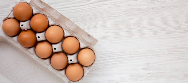 istock Raw Brown Eggs in a paper box, top view. Flat lay, overhead, from above. Space for text. 1303562395