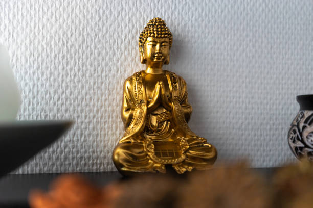 istock Golden Buddha statue inside house in front of a white wall. 1303562695