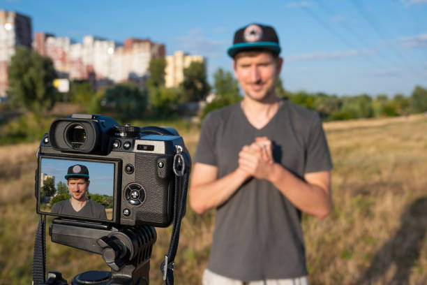 istock A male blogger in a park records a video on a camera in a park on a sunny day. Video tutorial, remote freelance work, lifestyle. 1303563477