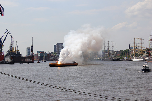 Burning Boat Accident with explosion in Hamburg Harbor Water Front Shipping Port for Boats and Ships causes danger for tourists by terrorism