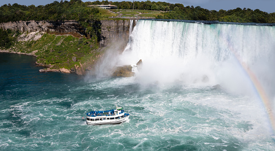 Giant Waterfalls with Mist coming of Cruise Ship tourist Ship Niagara Falls on the US Canadian Border in North America Hornblower and Maid of the mist Tourism Tourist Boats Tour to get close to waterfall