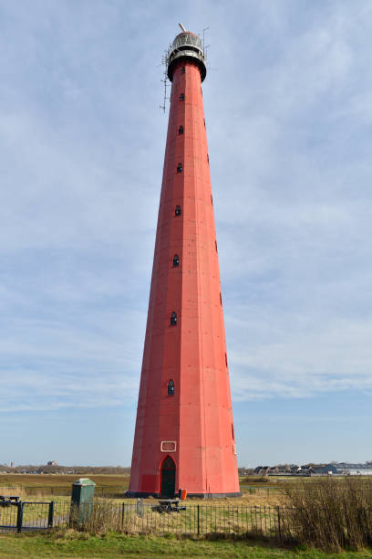 istock A tall red lighthouse beside the beach at Atlantikwall, Netherlands 1303563880