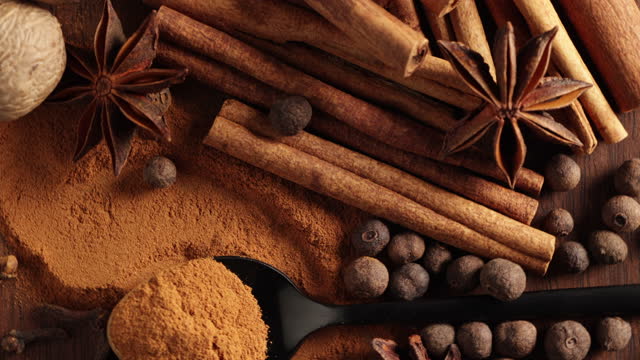 close up of various spices rotating on wooden table top view