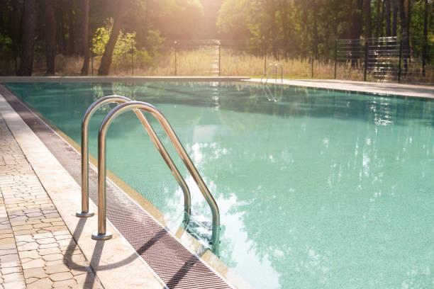 istock Big luxury empty rectangular swimming pool with clean blue water and ladder at tropical forest beach resort at sunrise morning light and nobody outdoors. Healthy leisure lifestyle travel and exercise 1303574985