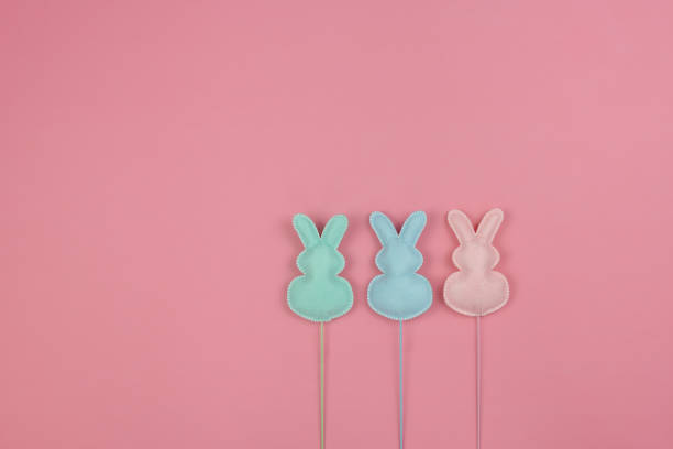 istock Three pastel bunnies in a row on a pink background for Easter 1303577231