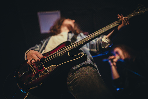 Hitting the Note: Music band singing and playing instruments on an indoor stage with colored lighting during a live concert