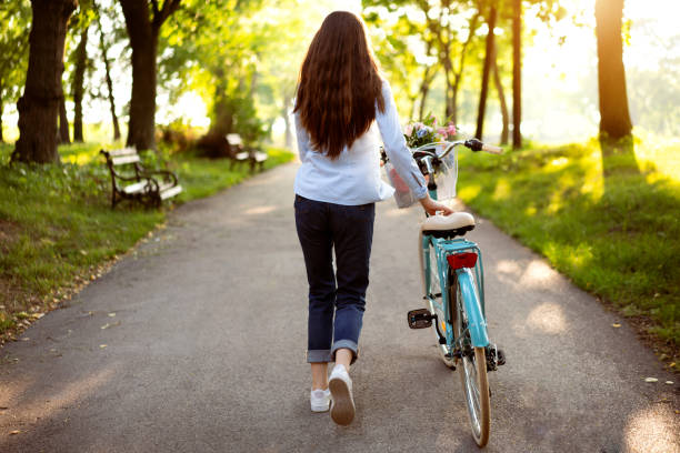 istock Rear view on a young woman pushing her retro bicycle 1303581757