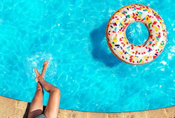 istock Woman's legs, inflatable doughnut swim in pool 1303581884
