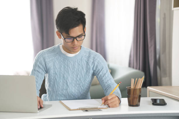 istock asian young student man entrepreneur working with computer studying learning online at home. e-learning webinar meeting. social distance in covid pandemic 1303582097