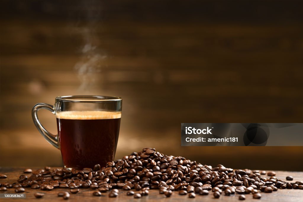 Cup glass of coffee with smoke and coffee beans on old wooden background Coffee - Drink Stock Photo