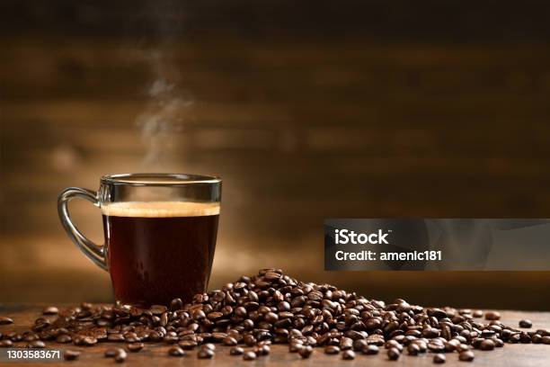 Cup Glass Of Coffee With Smoke And Coffee Beans On Old Wooden Background Stock Photo - Download Image Now