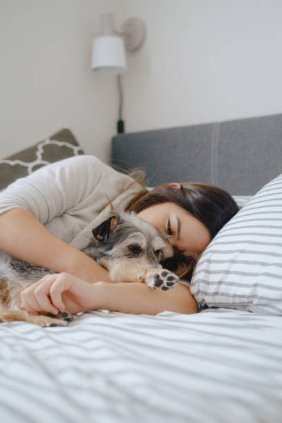 istock Woman cuddles dog in bed 1303587566