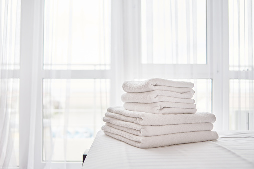 Pila de toallas de baño blanco fresco en la sábana en el interior moderno del dormitorio del hotel con ventana en el fondo, espacio de copia photo