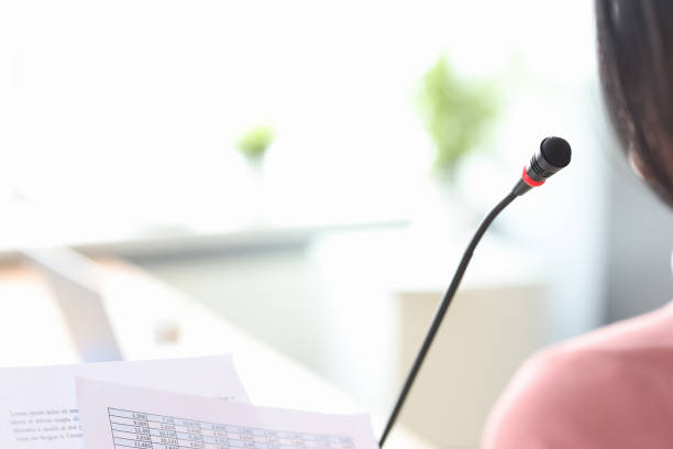 istock Man standing in front of microphone at conference closeup 1303589848