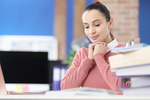 Young woman reading book and smiling in office. Business education concept