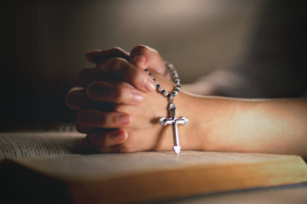 hands of religious christian woman holding jusus cross rosary praying to god with holy bibble book in chruch hands of religious christian woman holding jusus cross rosary praying to god with holy bibble book in chruch rosary beads stock pictures, royalty-free photos & images