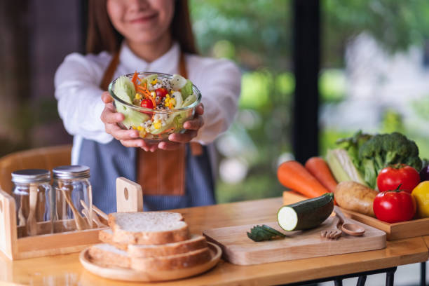 istock a female chef cooking and holding a fresh mixed vegetables salad in kitchen 1303598555