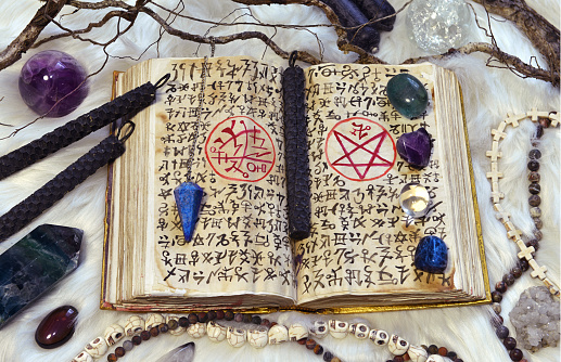 Open grimoire book of magic spells and ritual objects. Esoteric, gothic and occult background, Halloween mystic concept, no foreign language, only fantasy symbols.