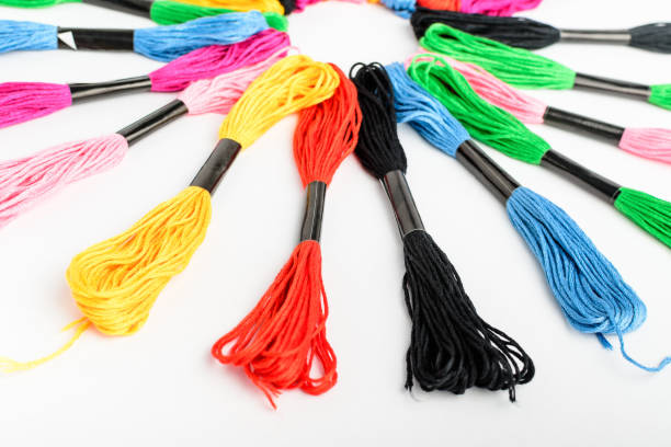 istock Many mixed vivid colored sewing threads for embroidery displayed in a circle isolated on a white table, side view of red, pink, yellow, blue, black and green textile materials 1303615942