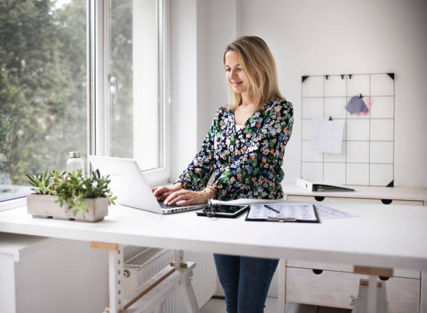 Businesswoman working at ergonomic standing workstation. Businesswoman working at ergonomic standing workstation. standing desk photos stock pictures, royalty-free photos & images