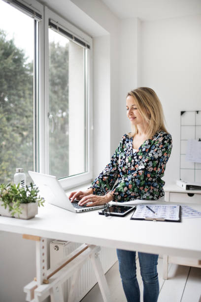 istock Businesswoman working at ergonomic standing workstation. 1303620008