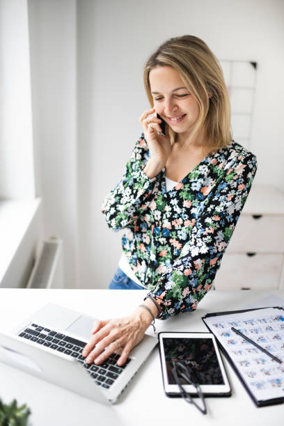 istock Businesswoman telephoning customer using cellphone while working at ergonomic standing desk. 1303620078