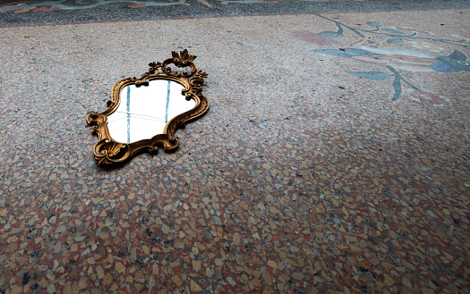 Ancient broken mirror on mosaic flooring.