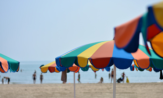 Striped beach umbrella near sunbed with vacationist's stuff on sandy coast, aerial view. Space for text