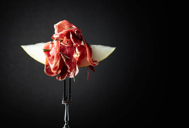 istock Melon with prosciutto and rosemary on a black background. 1303623577