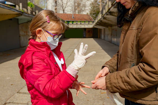 istock Mother is putting medical gloves on daughter's hands 1303625246