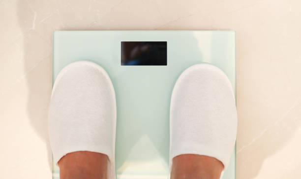 Human feet standing on the white digital weight scales