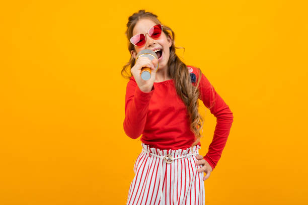 istock young singer with a microphone in her hands on a yellow studio background 1303630564