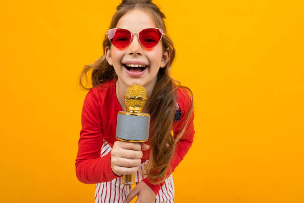 istock pretty presenter with microphone on yellow background close-up 1303630583