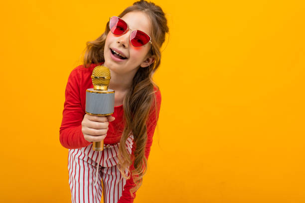 istock pretty presenter with microphone on yellow background close-up with copy space 1303630597