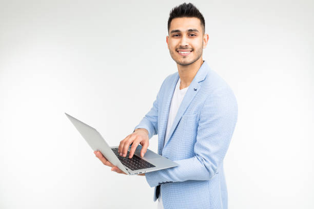 istock young attractive businessman is typing a message on a laptop on a white studio background with copy space 1303630623