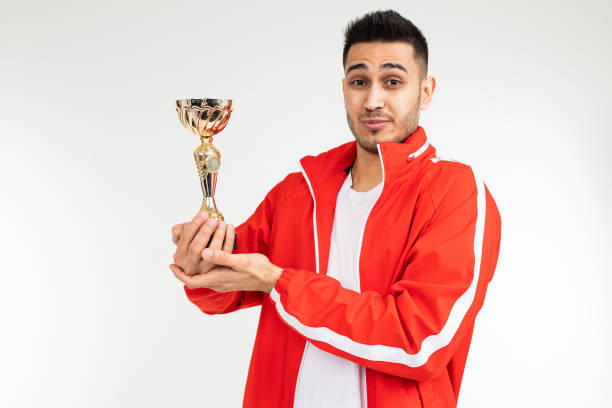 istock modest athlete in a tracksuit with a golden winner cup on a white studio background 1303630863