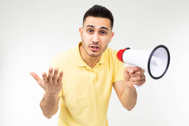 istock cool brunette man in a yellow T-shirt with a megaphone in his hands on a white studio background 1303630951