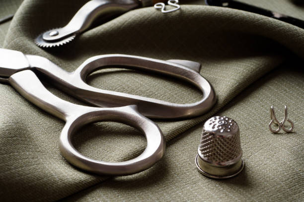 istock Sewing supplies lie on draped fabric, close-up. Sewing background. Spools of thread, a centimeter, scissors, a thimble, on a gray draped cloth. Atelier concept. Fashion designer. Sewing composition 1303633664