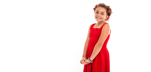 Portrait of little caucasian girl with fair hair and pretty face in red dress smiles and rejoices
