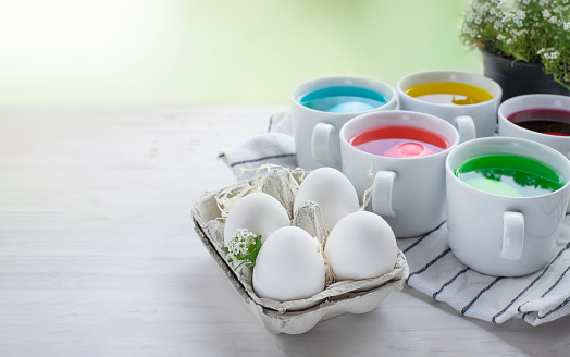 Easter eggs dye process and eggs in carton on  light wooden background. Image with copy space