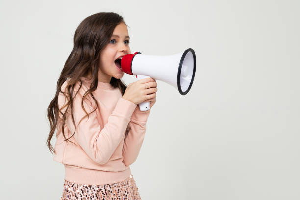 istock girl with a megaphone in hand sideways on a white studio background with copy space 1303634638