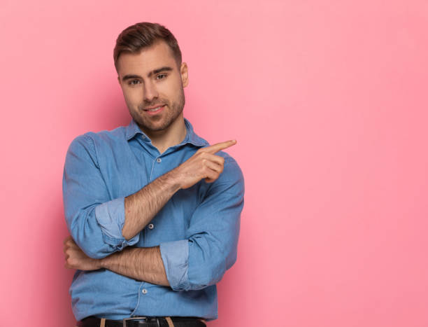 istock attractive unshaved guy in denim shirt pointing finger to side 1303636133