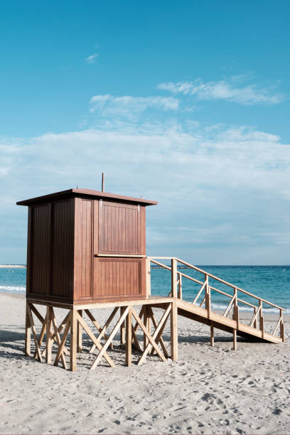 detail of a wooden lifeguard tower in a lonely beach close to the seashore, with the ocean in the background