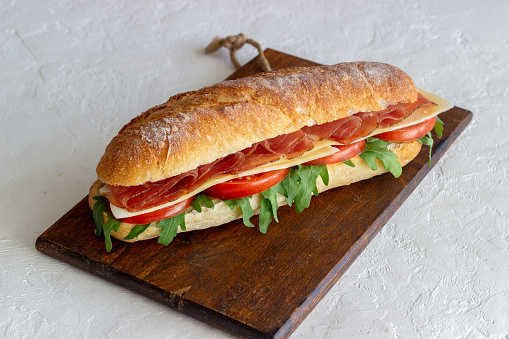 Sandwich with prosciutto, tomatoes, arugula and cheese. Healthy eating Diet