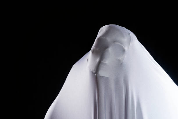 istock White ghost in white cloth on isolated black background. Face devil shouting covered curtain on blank. Halloween concept. 1303640162