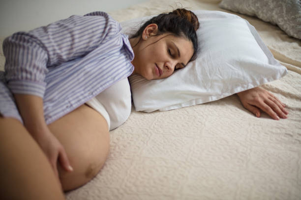 istock Pregnant woman sleeping on bed and touching her belly. 1303640248
