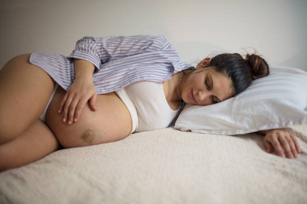 istock Pregnant woman sleeping on bed and touching her belly. 1303640272